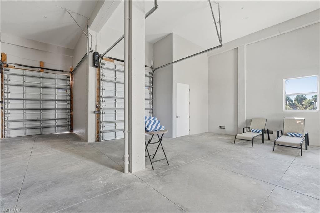 Spacious interior with high ceilings, concrete flooring, and multiple roll-up garage doors - Virtually Edited Image