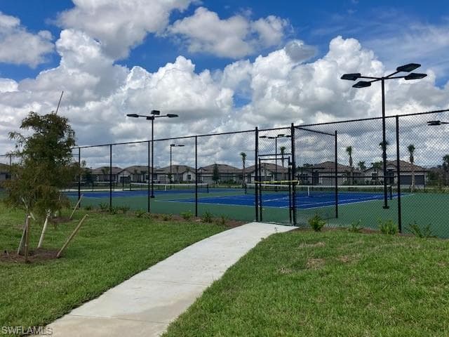 View of tennis court with a gate and a residential view