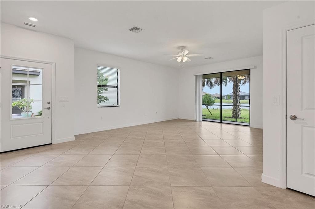 Unfurnished room featuring plenty of natural light, light tile patterned floors, ceiling fan, and a water view