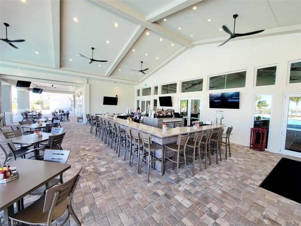 Dining area with beam ceiling, high vaulted ceiling, a ceiling fan, brick patterned floors, and recessed lighting