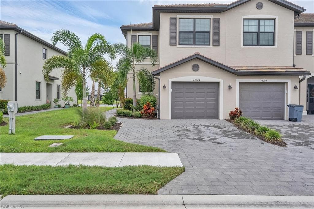 Mediterranean / spanish house with decorative driveway, a front yard, stucco siding, and a garage