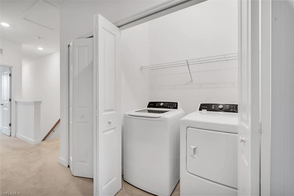 Laundry room with light colored carpet, washing machine and clothes dryer, and recessed lighting
