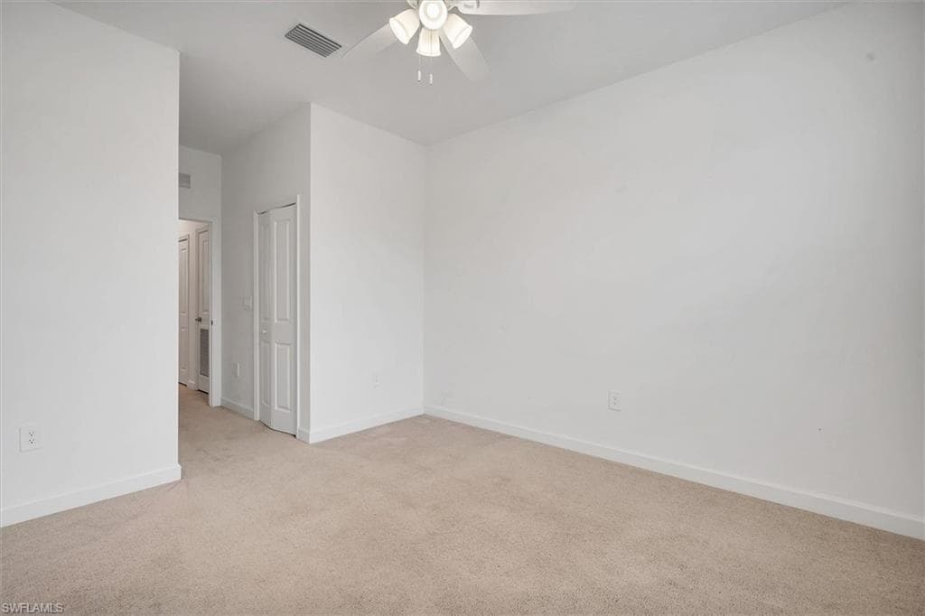 Unfurnished room featuring light colored carpet and a ceiling fan