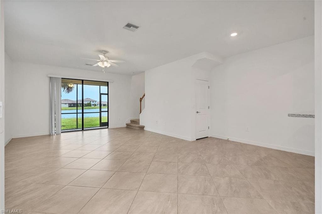 Spare room with stairs, light tile patterned floors, a ceiling fan, recessed lighting, and a water view