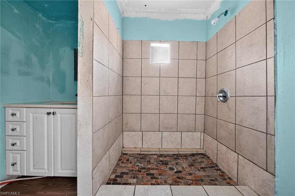 Tiled shower enclosure featuring a mosaic floor and a wall-mounted shower fixture