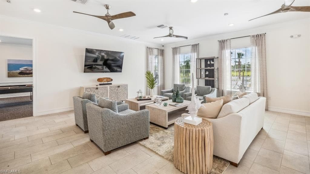 The property features a spacious living areawith light-colored tile flooring, multiplewindows offering natural light, and ceiling fans for comfort