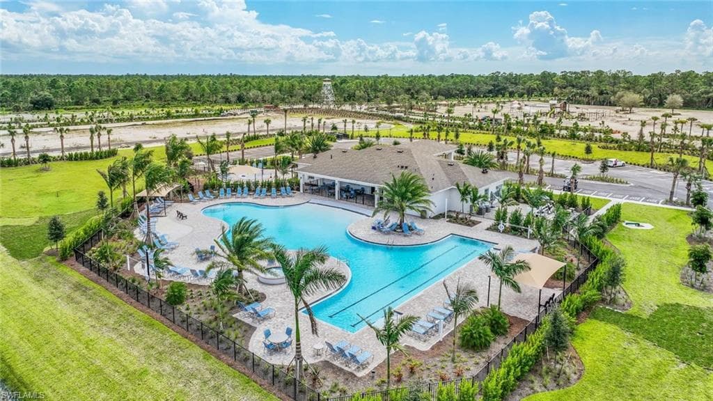 Outdoor pool area featuring a large swimmingpool, lounge chairs, and surrounding palmtrees