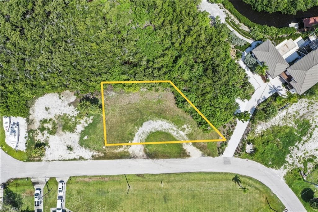 Cleared building lot bordered by natural vegetation and street frontage