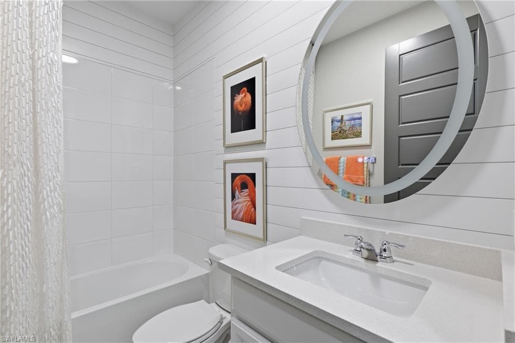 Beautifully appointed bath with designer finishes, a back lit mirror, shiplap wall and combination shower tub