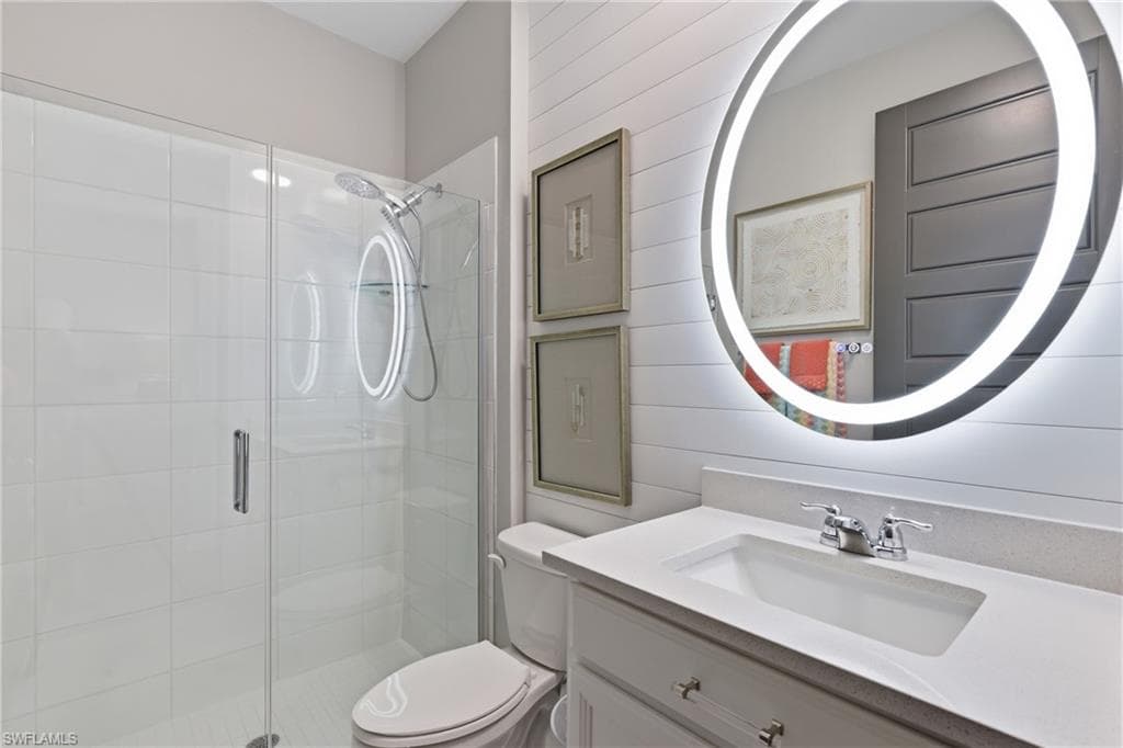 Stylish guest bath featuring a backlit mirror and glass enclosed shower