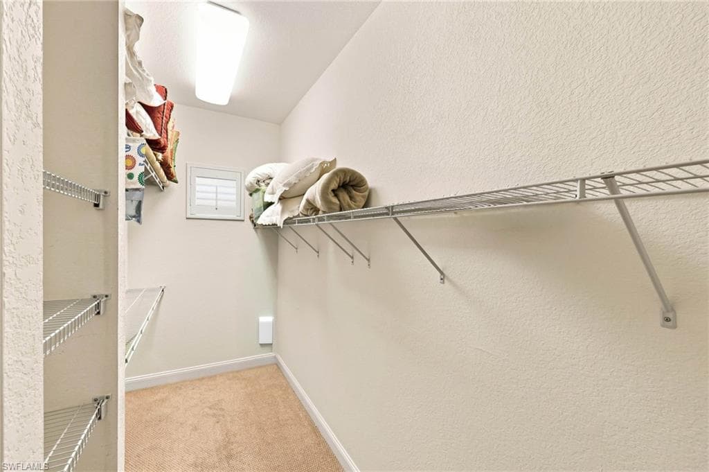 Spacious walk-in closet featuring floor-to-ceiling wire shelving with multiple tiers, cork-finish flooring, and abundant natural light from a transom window