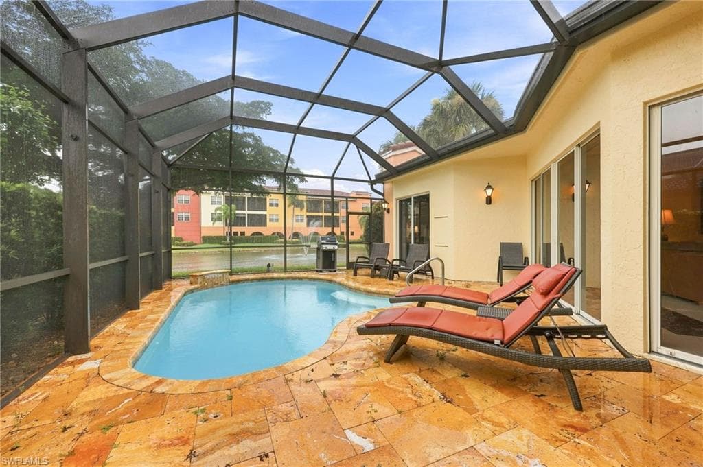 Screened lanai featuring a built-in pool, stone patio, and stucco exterior