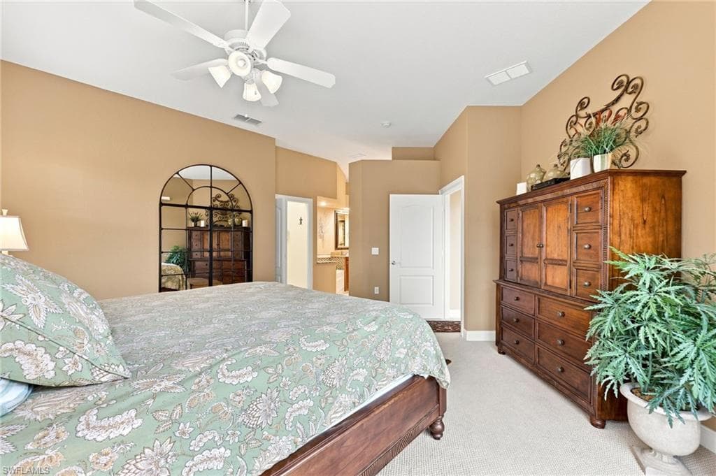 Spacious primary bedroom featuring warm neutral walls, ceiling fan with recessed lighting, and abundant natural light