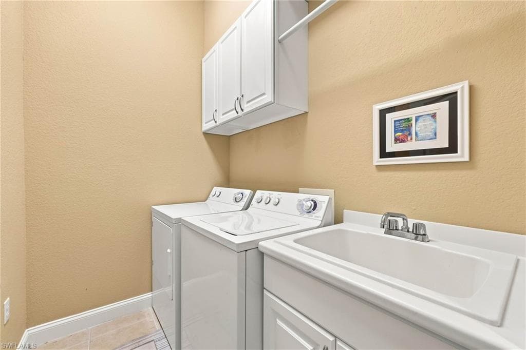 Dedicated laundry room featuring side-by-side washer and dryer units, white cabinetry with ample storage, laminate countertop workspace, and neutral wall finishes