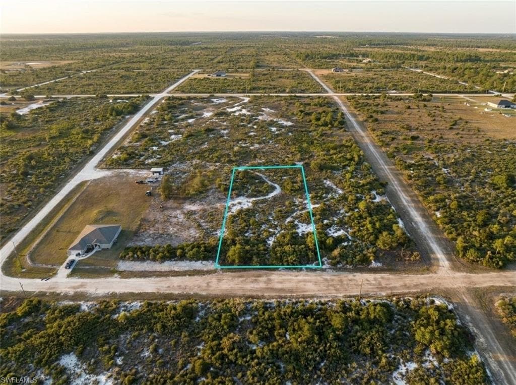 Expansive vacant land parcel, outlined in blue, featuring natural scrub brush and sandy terrain
