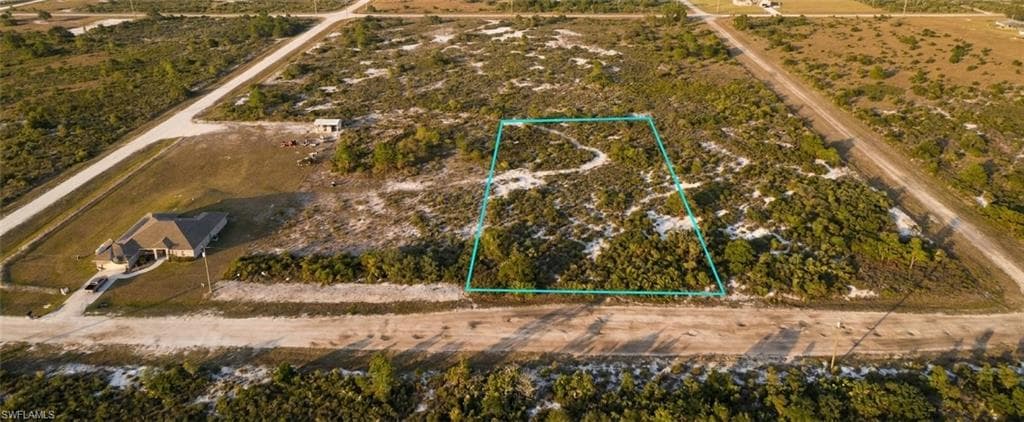 Expansive land parcel featuring natural shrubbery and visible dirt road access