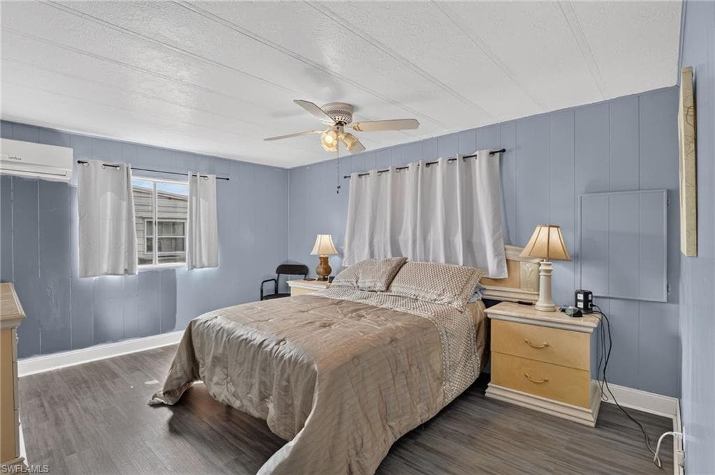 Bedroom featuring wood-finish flooring, blue paneled walls, and a white ceiling with a ceiling fan