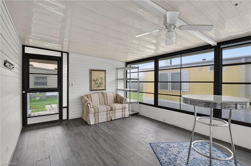 Enclosed patio featuring wood-finish flooring, white paneled walls, and a white ceiling with a ceiling fan