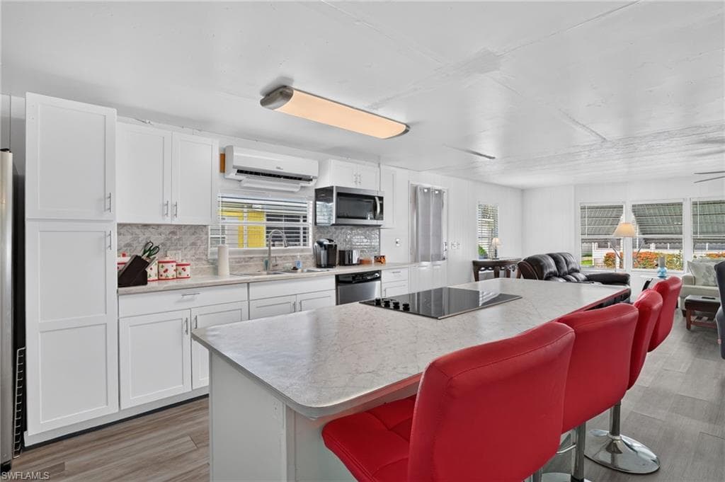 Kitchen featuring white cabinetry, grey-veined countertops, and a tile backsplash