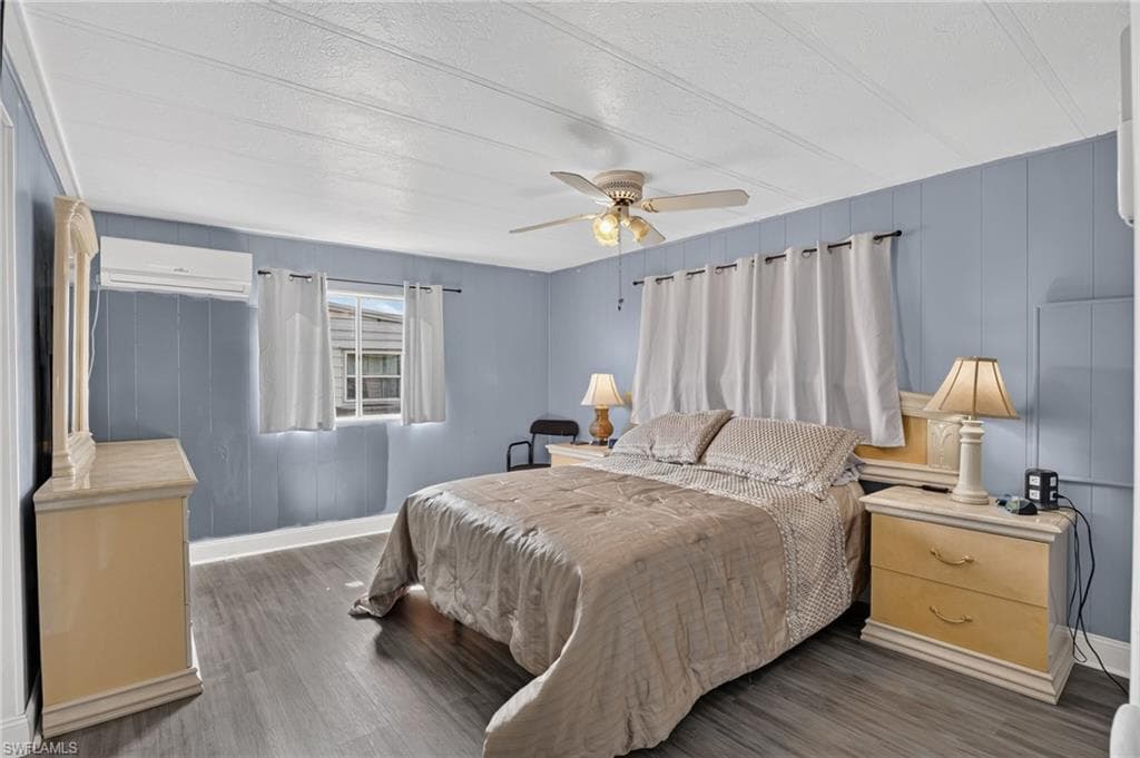 Spacious room featuring wood-finish flooring, a ceiling fan with integrated lighting, and multiple windows