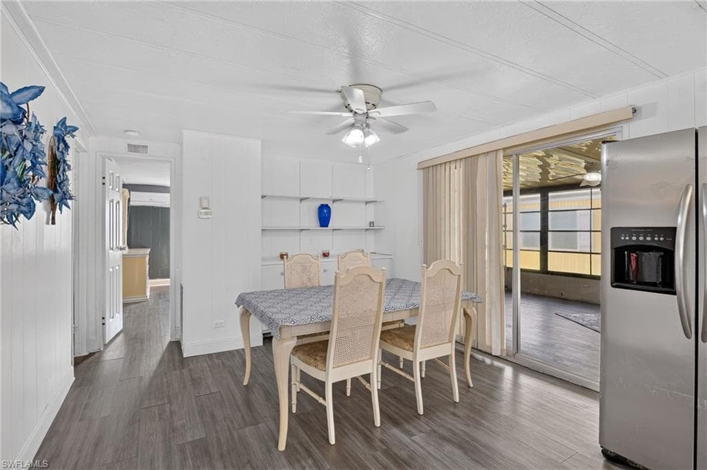 Dining area with wood-finish flooring, built-in shelving, and white paneled walls