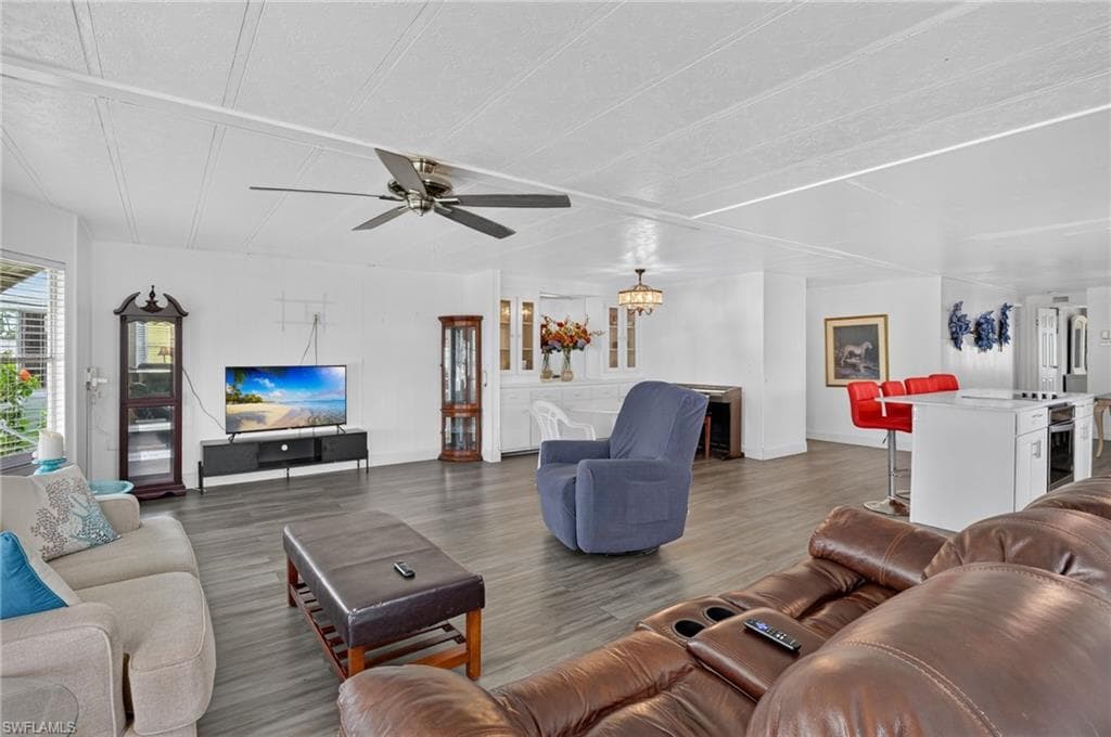 Expansive open-concept living area featuring wood-finish flooring, a ceiling fan with light fixture, and white wall finishes