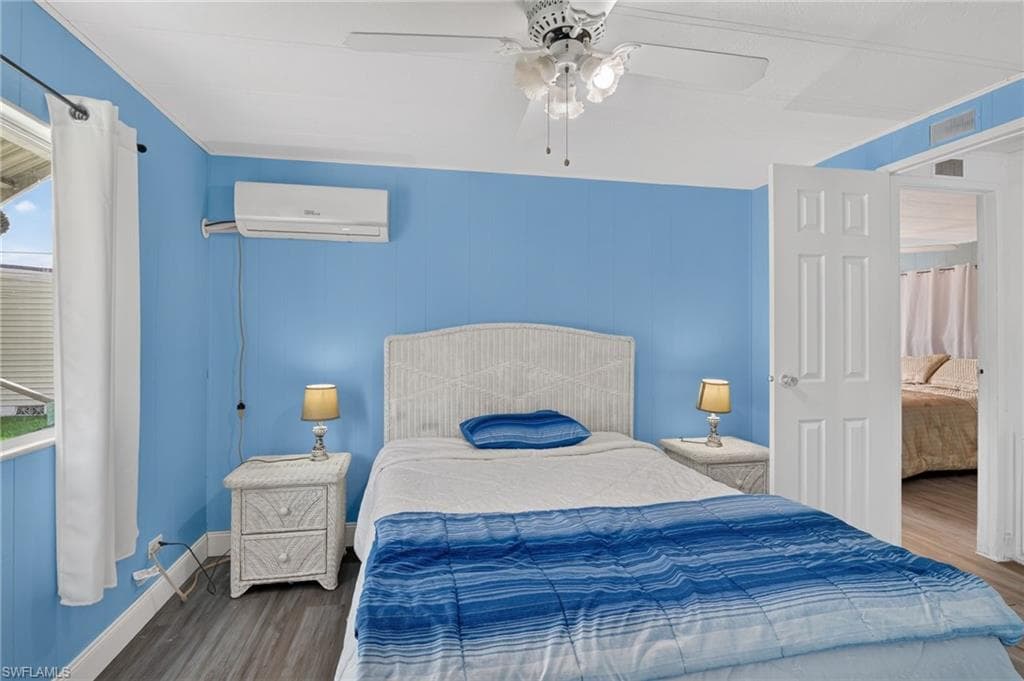 Bedroom featuring wood-finish flooring, a ceiling fan, and a mini-split air conditioning unit