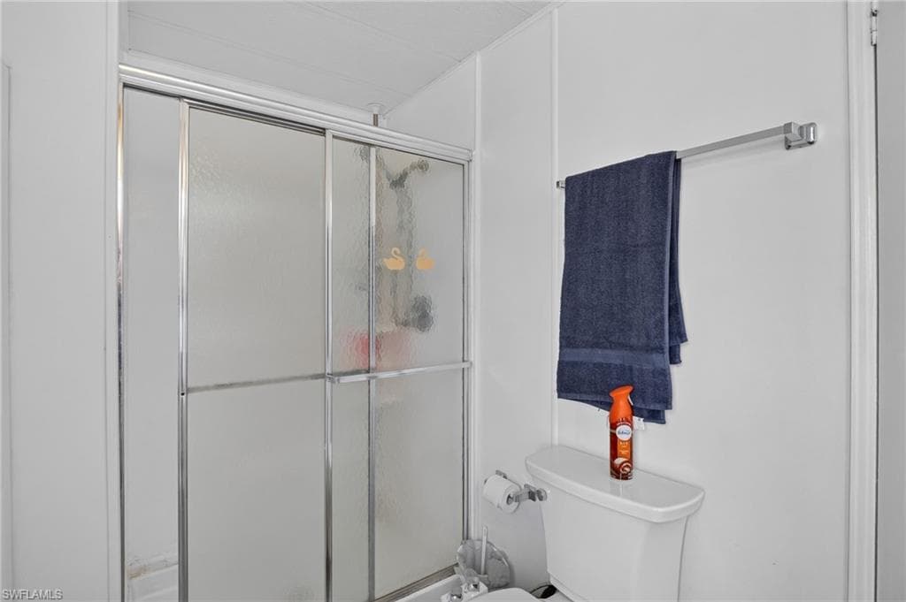 Bathroom featuring a shower with sliding frosted glass doors, a white toilet, and a wall-mounted towel bar