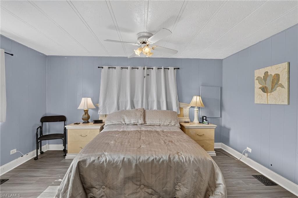 Interior room featuring light blue panel walls, white ceiling, and wood-finish flooring