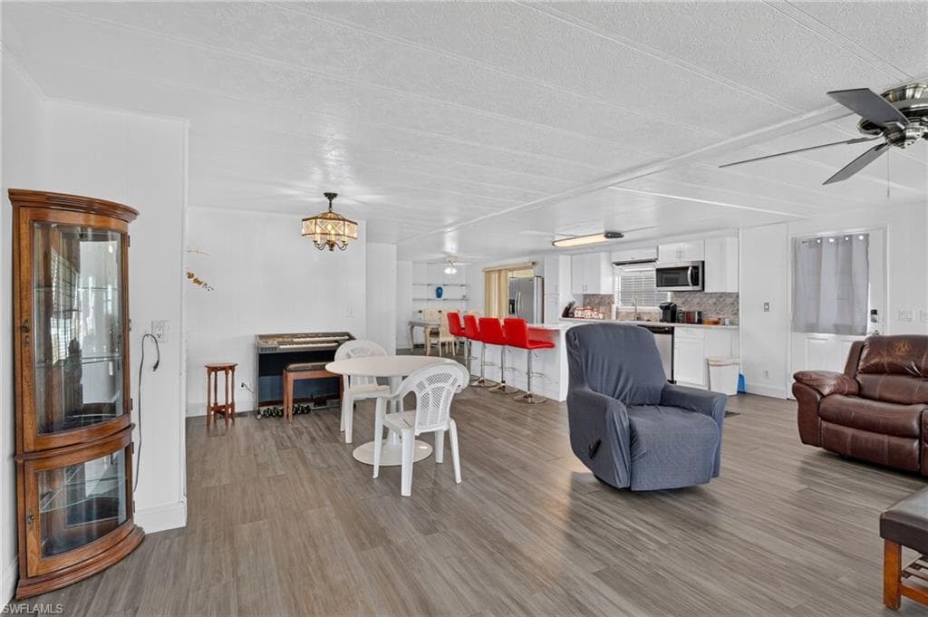 Open-concept living area featuring wood-finish flooring, white walls, and a ceiling fan