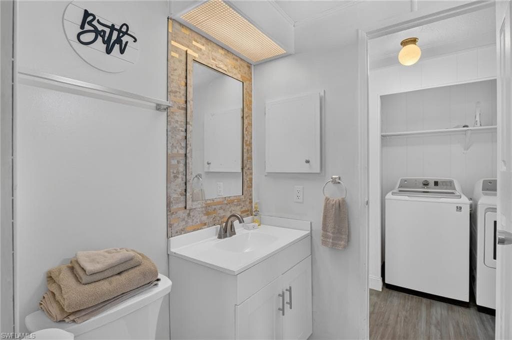 Bathroom vanity with a white rectangular sink, brushed nickel faucet, and a large mirror framed by stone-look wall tile