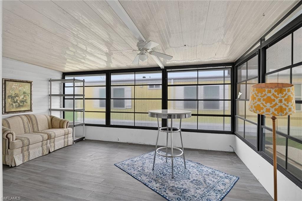 Sunroom featuring a paneled ceiling, ceiling fan, and wood-finish flooring