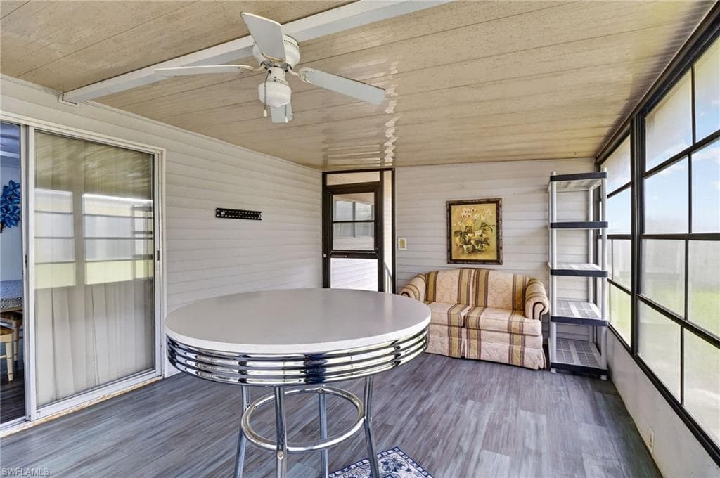 Enclosed patio featuring wood-finish flooring, a ceiling fan, and large windows