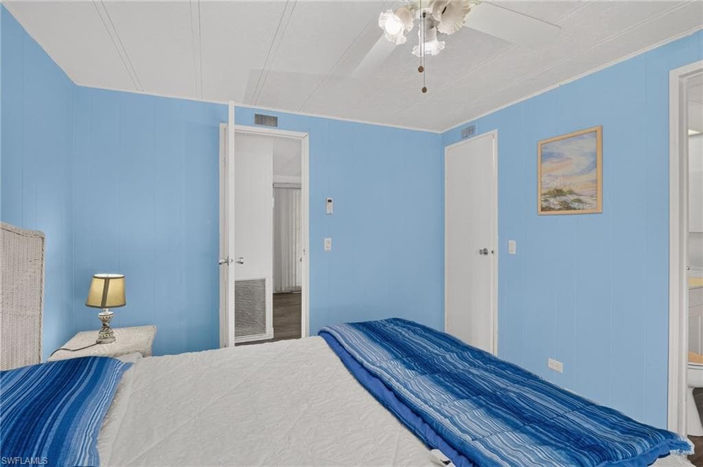 Bedroom featuring light blue paneling, white textured ceiling, and a ceiling fan with light fixture