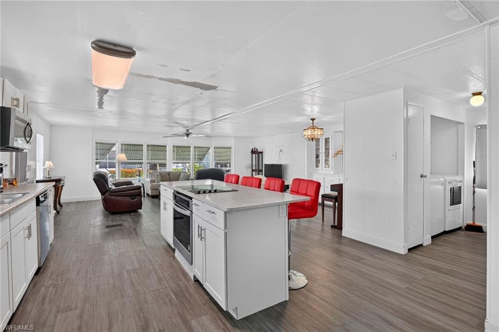 Kitchen island with a built-in cooktop and oven, white cabinetry, and light-toned countertops