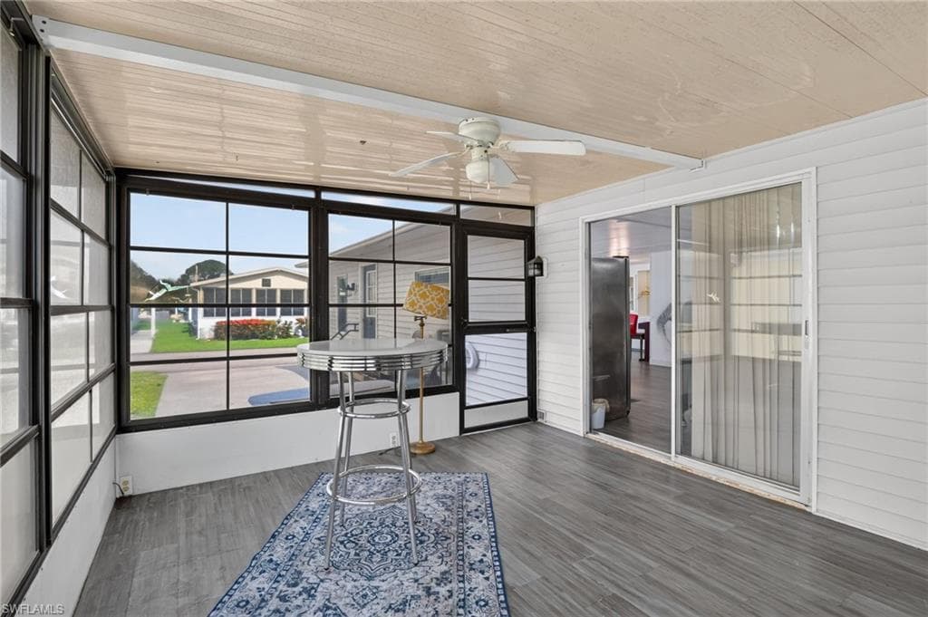 Enclosed patio featuring expansive windows, wood-finish flooring, a ceiling fan, and sliding glass door access