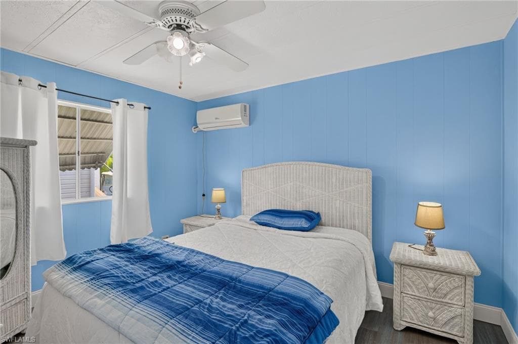 Room featuring wood-finish flooring, a ceiling fan with integrated lighting, and a wall-mounted mini-split air conditioning unit