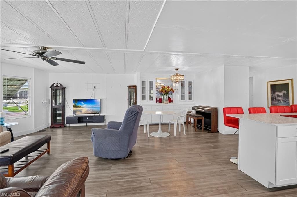 Open-concept living area featuring wood-finish flooring, white walls, and a ceiling fan