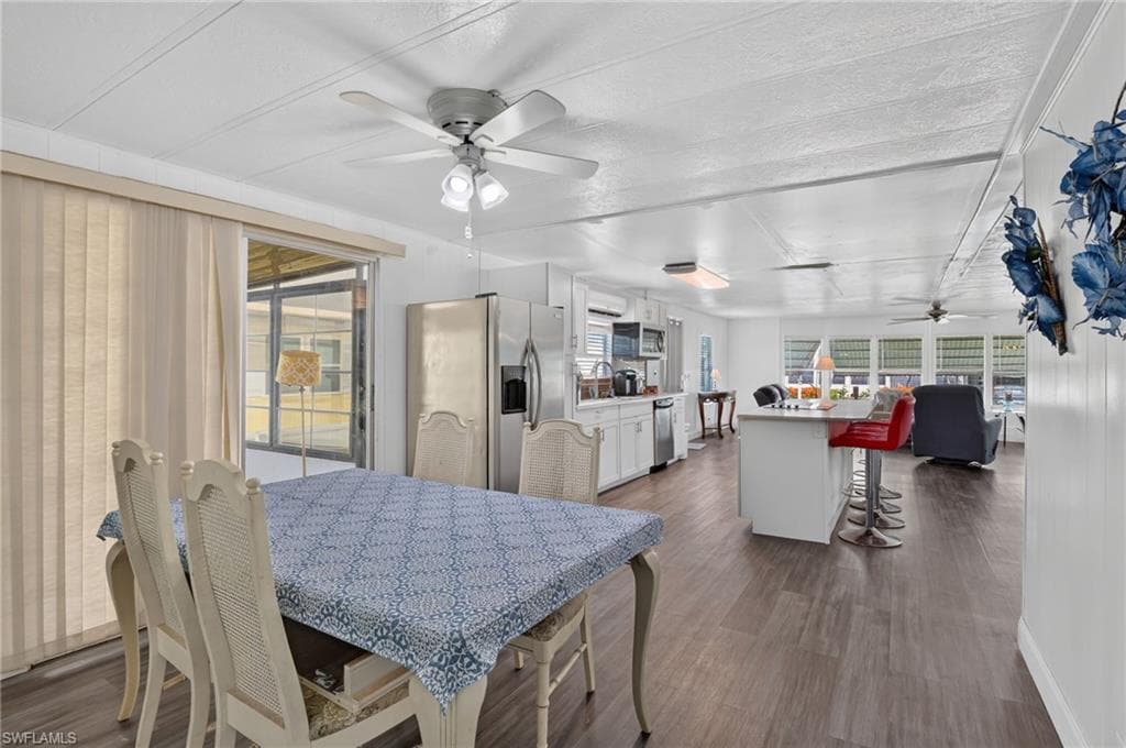 Open-concept interior featuring wood-finish flooring, white paneling, and a kitchen island with seating