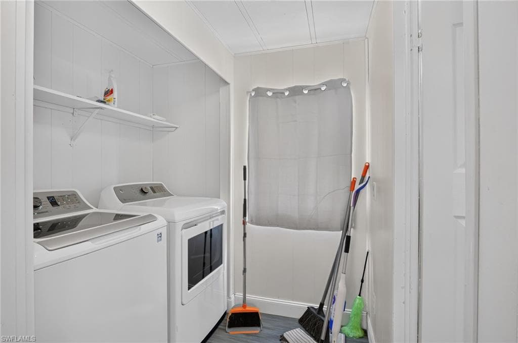 Dedicated laundry area featuring a washer and dryer, an overhead shelf for storage, paneled walls, and wood-finish flooring