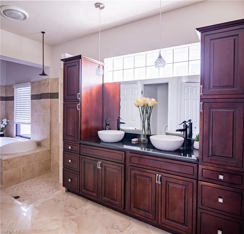 Dual vessel sinks with wall-mounted black faucets, dark wood cabinetry, and a full-width vanity mirror