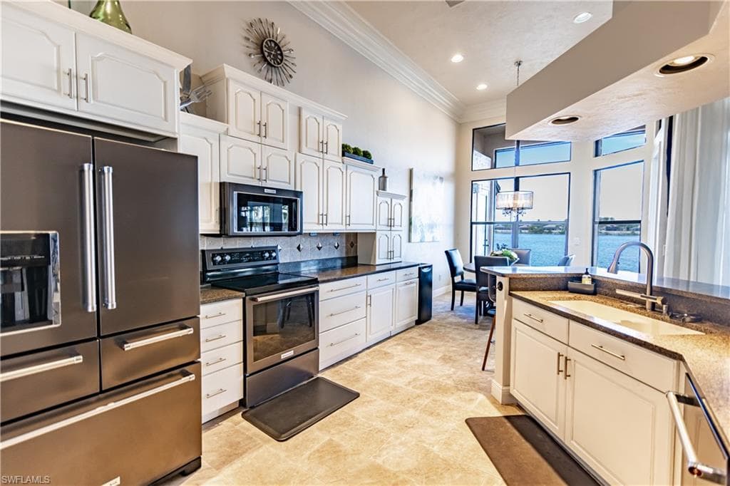 Kitchen featuring light-finish cabinetry with contrasting dark countertops, integrated stainless steel appliances, recessed lighting, and tile flooring