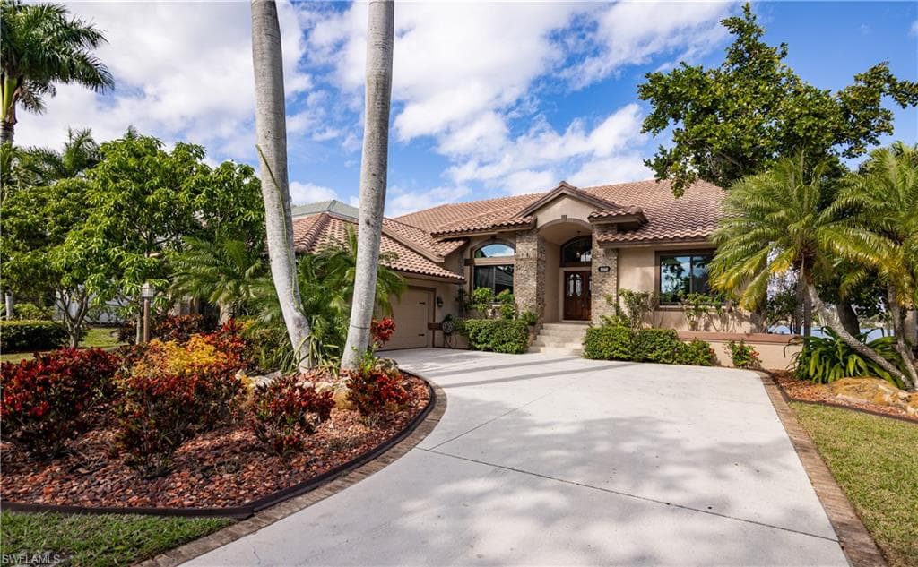 Mediterranean-style residence featuring a tile roof, stucco exterior, and stone facade accents