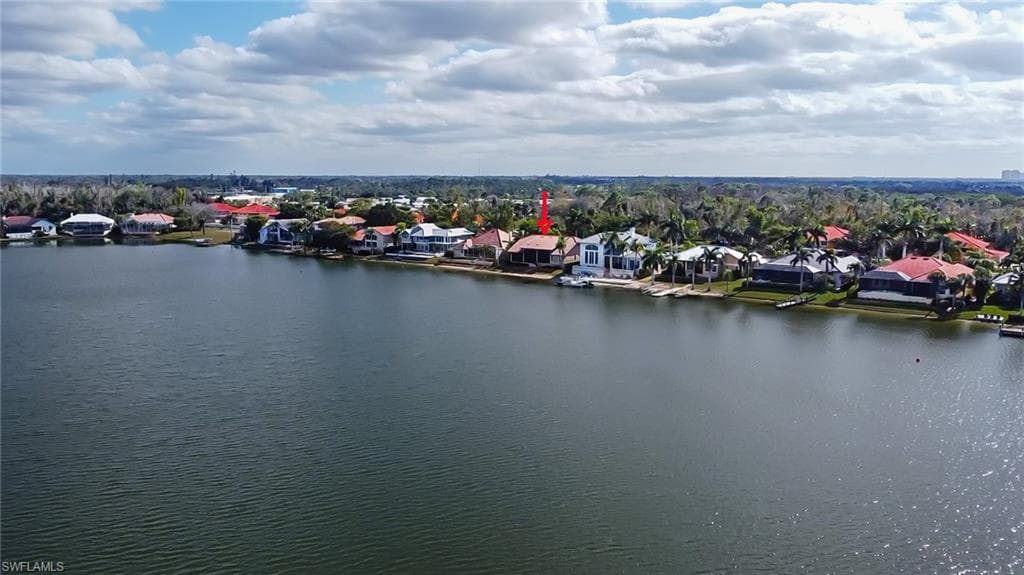 Waterfront residence featuring a private boat dock, expansive rear patio, and mature palm trees