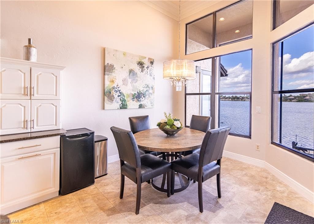 Dining area featuring expansive windows, water views, a built-in cabinetry unit with a dark countertop, and tile flooring
