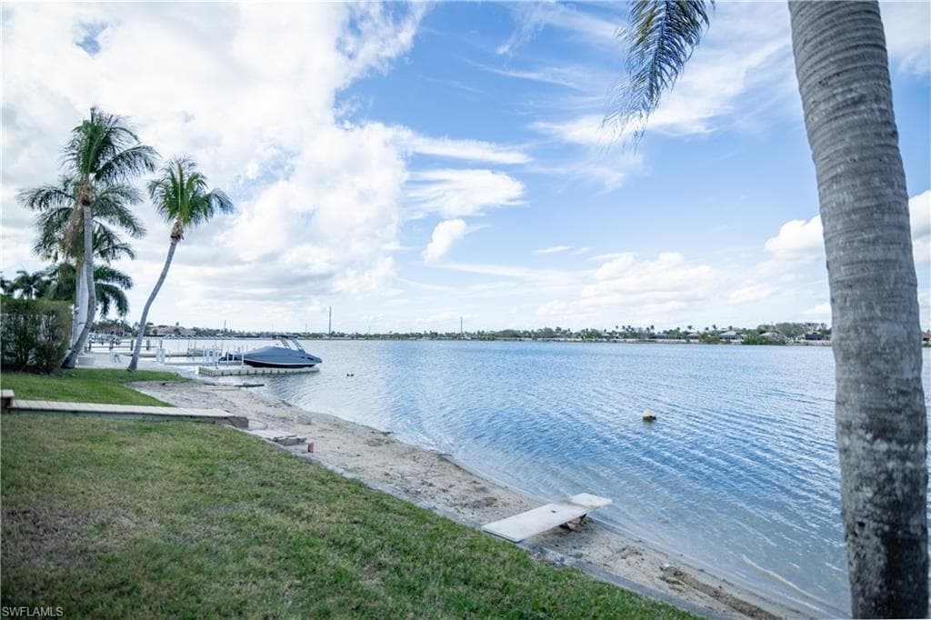 Expansive waterfront property featuring a private sandy beach, mature palm trees, and a private boat dock with a vessel