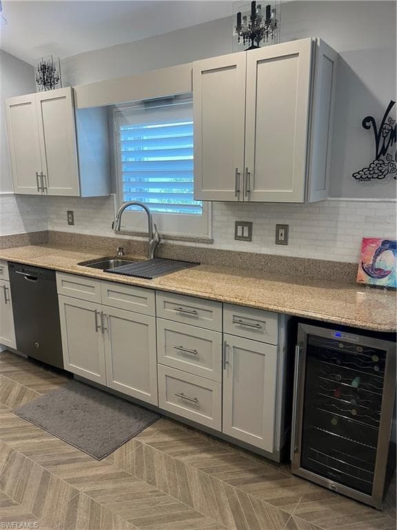 Kitchen featuring light-toned cabinetry with brushed nickel hardware, a stainless steel sink with a gooseneck faucet, light-colored granite countertops, and a white subway tile backsplash