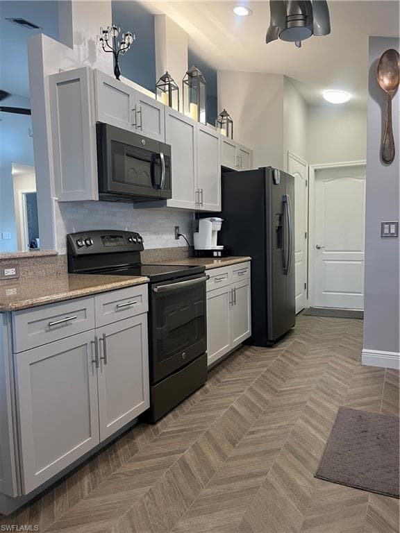 Modern kitchen featuring light gray cabinetry, stainless steel hardware, and speckled countertops