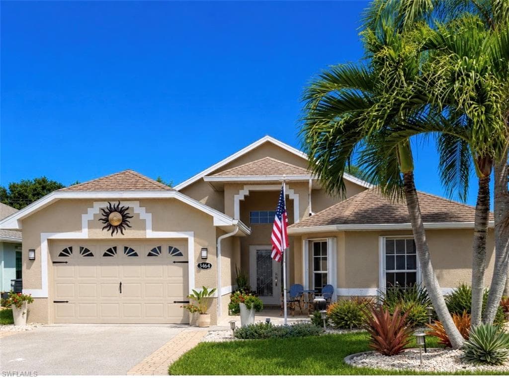Stucco exterior with a two-car garage and decorative sunburst accent