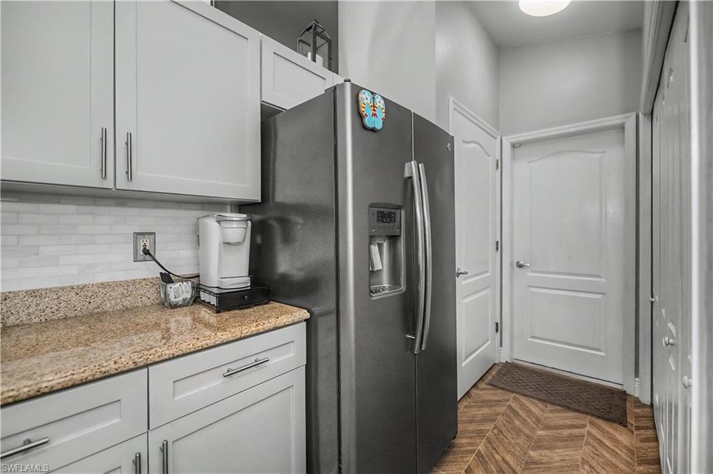 Modern kitchen area featuring light gray cabinetry with brushed nickel hardware, a light-toned granite countertop, and a white subway tile backsplash